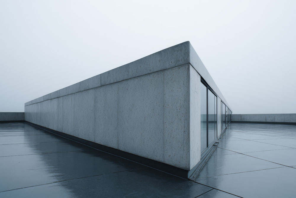 Flat commercial rooftop finished with a seamless waterproofing membrane surrounding a modern concrete building.
